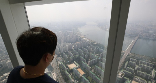 한 시민이 롯데월드타워 서울스카이에서 송파구 한강변 아파트를 바라보고 있다.<연합뉴스>